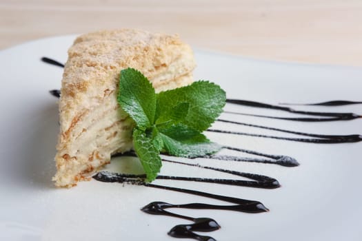 Piece of napoleon cake on plate with chocolate sauce. Puff pastry cake with custard