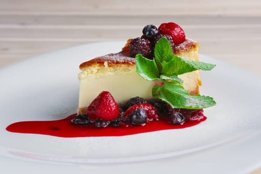 Cheesecake with berries sauce and green mint leaf.