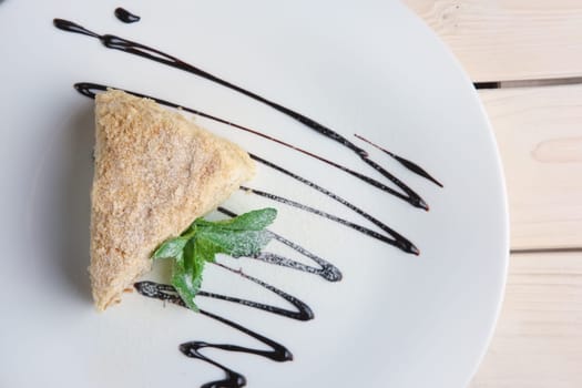 Top view of napoleon cake on plate with chocolate sauce. Puff pastry cake with custard