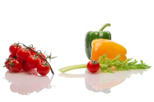 A branch of a tomato, celery and bell pepper with water drops and reflection on white background