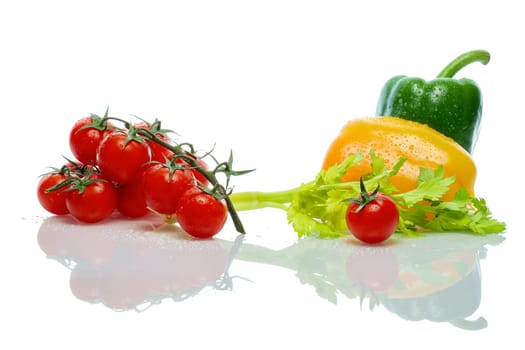 A branch of a tomato, celery and bell pepper with water drops and reflection on white background