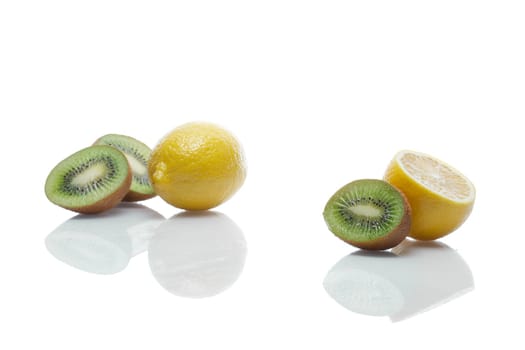 Lemons and kiwi with reflection on white glass table