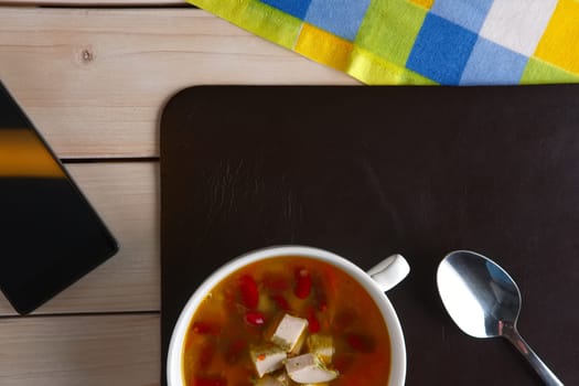 Top view of table with lunch. Plate of bean soup with meat.