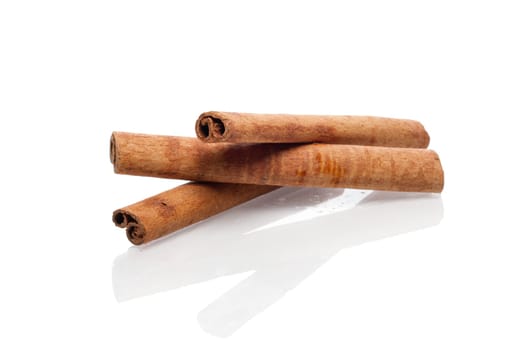 Three cinnamon sticks with reflection on white background.
