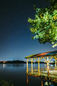 Night Stars Above Lake. Natural Starry Sky Landscape. Wooden Pier
