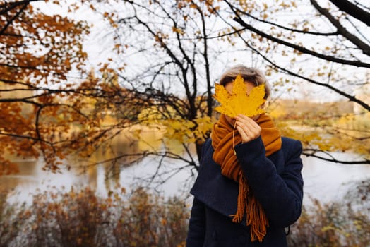 Faceless portrait of a short-haired blonde in the autumn in the park.