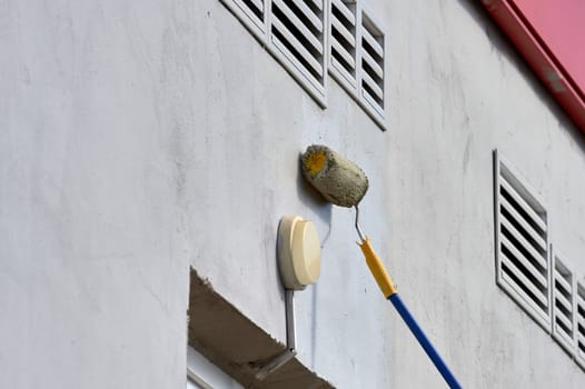 painting the street wall with a roller with gray paint. High quality photo