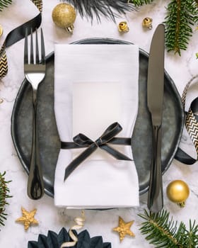 Black and golden Table setting with ornaments and fir tree branches top view, place card mockup. Christmas or New Year atmospheric composition flat lay, copy space.