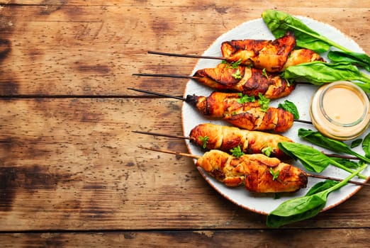 Roasted chicken meat. Chicken breast on a skewer. Meat kebab or shashlik with peanut sauce.
