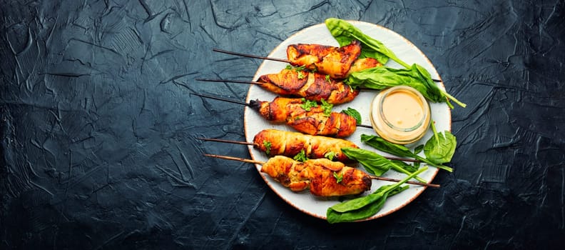 Roasted chicken meat. Chicken breast on a skewer. Meat kebab or shashlik with peanut sauce.