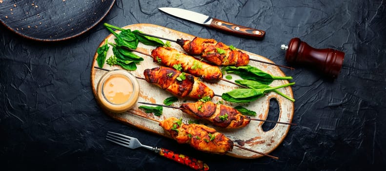 Roasted chicken meat. Chicken breast on a skewer. Meat kebab or shashlik with peanut sauce.