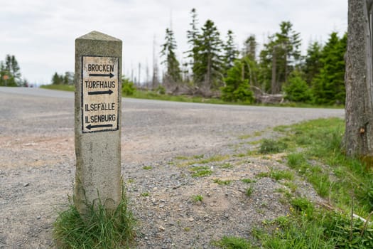 Stone signposts in the Harz National Park with directions to Torfhaus, Ilsenburg, Ilse waterfalls, and the Brocken summit.