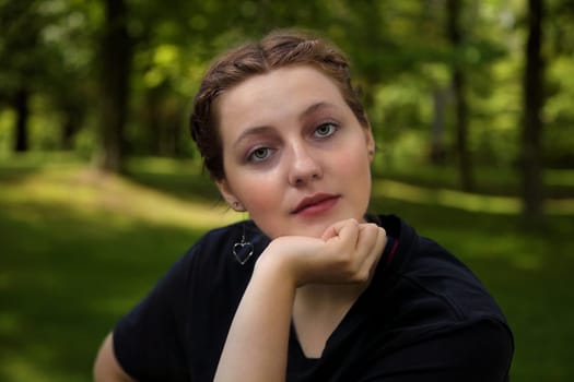 young woman daydreaming outside looking at camera pensive thoughtful student girl leaning on her chin