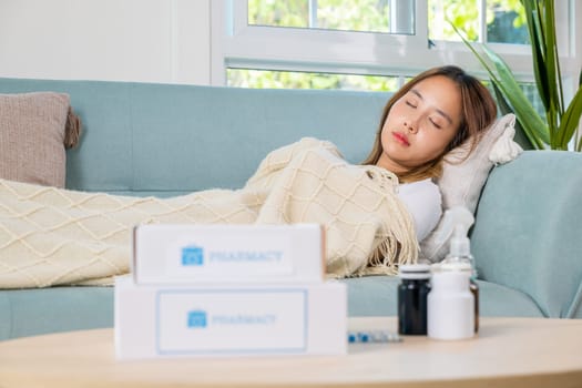 Asian beautiful female use pharmacy first aid kit box delivery service from hospital, Young woman tired sick she sleep and resting on sofa after take medicines pills in living room at home, healthcare
