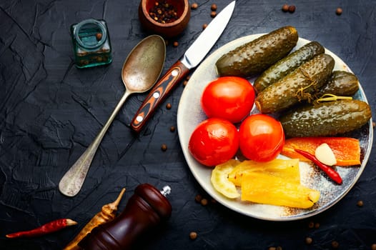 Salted vegetables on a plate. Pickled cucumbers, tomatoes and peppers.