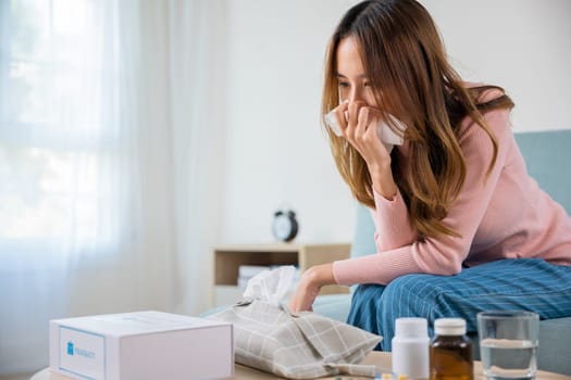 Sick woman. Beautiful female health problem blowing nose use pharmacy kit box delivery service from hospital, delivery pharmacy concept, Asian young girl cold sick she sneeze with tissue paper on sofa