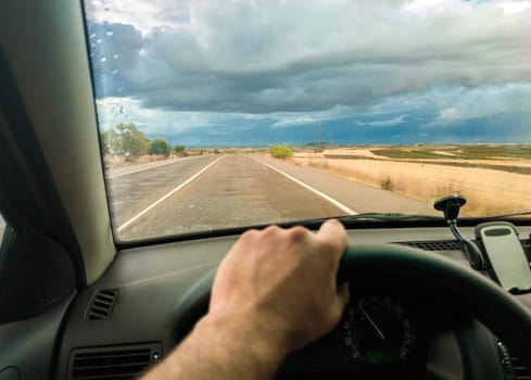 Driving under sunset stormy sky. View from the inside of the car