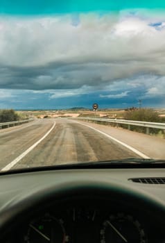 Driving under sunset stormy sky. View from the inside of the car