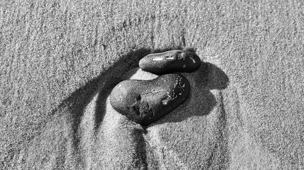 heart-shaped stone in the sand of the beach on the Baltic Seaa black and white. Romantic symbol for people in love. Small sign as still life.