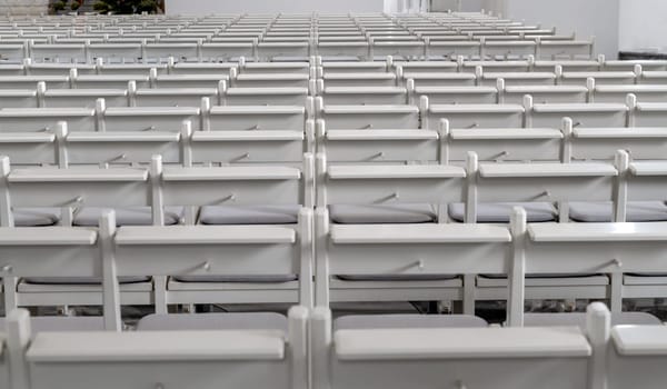 Many empty white benches stand in rows one behind the other
