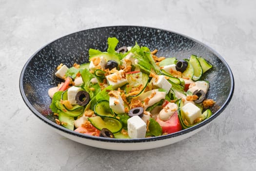 Salad with lettuce, cucumber, olives, tomato, feta cheese and bacon chips