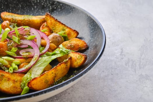 Closeup view of fried potato wedges with champignons dressed with red and white onion
