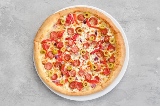 Top view of small size pizza with thin sausage, bell pepper, olives and onion