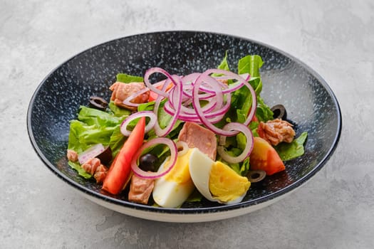 Salad with lettuce, salmon, tomato, boiled egg and onion with olives