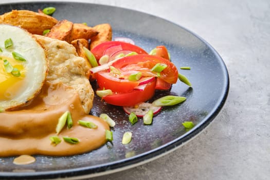 Closeup view of chopped pork sirloin with fried potato wedges, egg, fresh tomato and radish