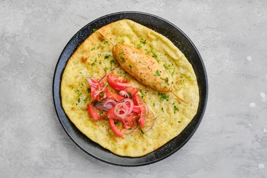 Top view of kebab served on tortilla with tomato and red onion