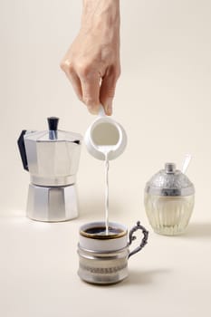 Coffee concept - pouring milk in cup of coffee, geyser coffee maker and shugar