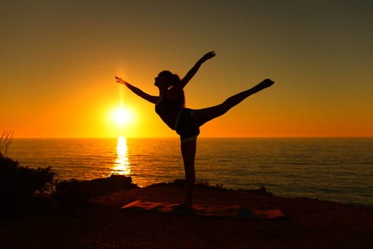 Backlight ballerina silhouette danding ballet at sunset on the beach