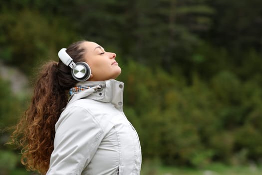 Profile of a hiker with headphones breathing fresh air in the mountain