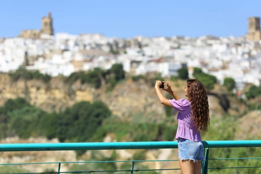 Tourist taking photos of a town with smart phone on summer vacation