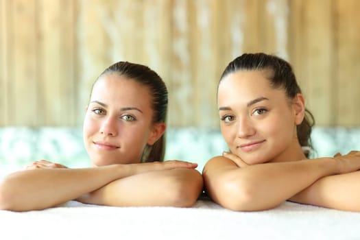 Two beautiful women posing looking at camera in a spa pool
