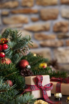 Wrapped gift boxes between Christmas decorations, pine cones and green fir branches close up against stone wall. Christmas or New Year Holiday atmosphere flat lay