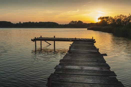 Sunset over a quiet lake with a wooden pier