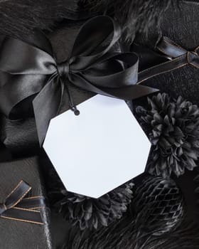 Wrapped Gift Boxes with black paper flowers and decorations and square gift tag, mockup, copy space. Dark composition with blank label card for Birthday, Anniversary or black party present