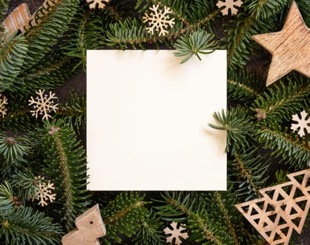Blank card between rustic wooden Christmas decorations and green fir branches top view. Square card mockup, flat lay, copy space. Christmas or New Year greeting card template, Holiday stationery