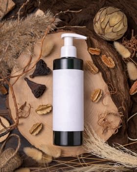 Refillable one pump bottle on wood near natural boho decorations top view, label mockup. Skincare beauty product, lotion or essence. Bohemian eco friendly cosmetics flat lay with dried leaves.