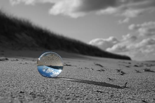 glass globe on the beach of the baltic sea. Black and white photo with a color glass ball