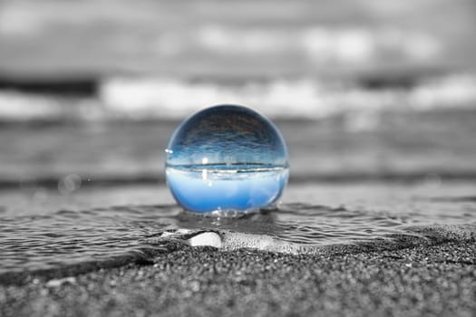 glass globe on the beach of the baltic sea. Black and white photo with a color glass ball