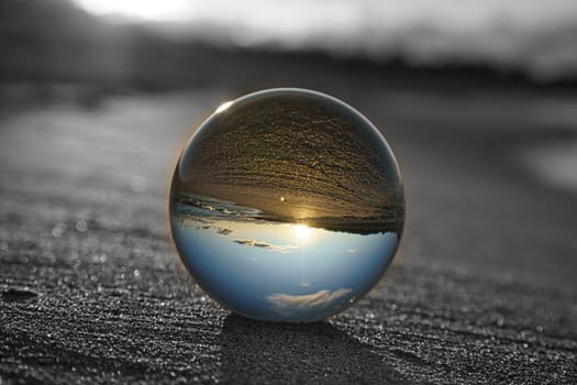Glass globe on the beach of the Baltic Sea in Zingst in which the landscape is depicted. The surroundings are depicted in black and white, only in the glass sphere reflect the colors of nature