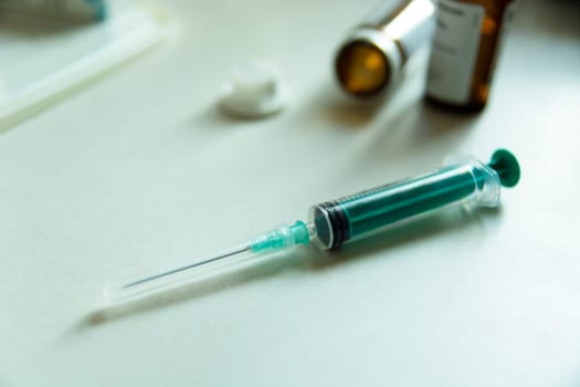 A syringe with a needle on the table top and a medicine pack, close up