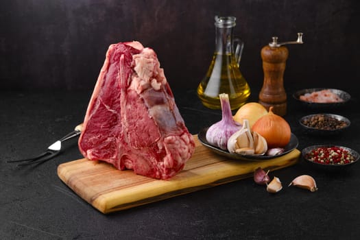 Raw porterhouse steak with ingredients for cooking on wooden log