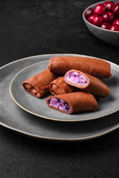 Thin chocolate pancakes stuffed with curd, blueberry and cherry