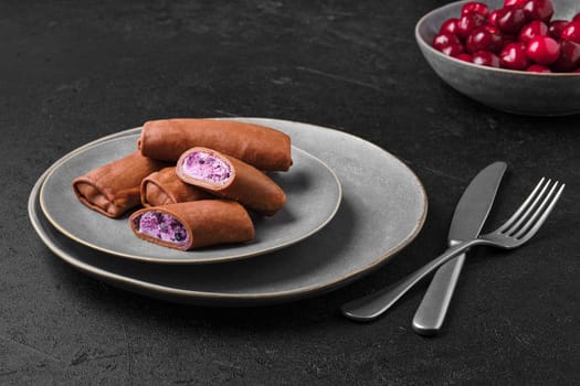 Thin chocolate pancakes stuffed with curd, blueberry and cherry