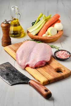 Raw fresh whole chicken breast with skin on carcas with ingredients for cooking