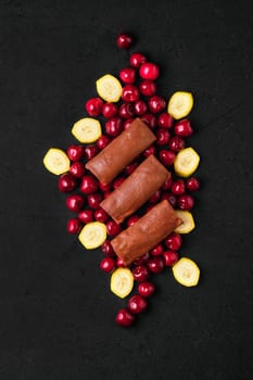 Overhead composition with thin chocolate pancakes stuffed with curd, cherry and banana