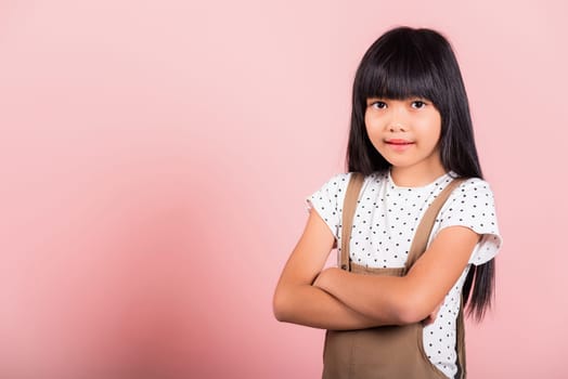 Asian little kid 10 years old smiling with arms crossed at studio shot isolated on pink background, Portrait of Happy confidence child girl lifestyle, Positive person